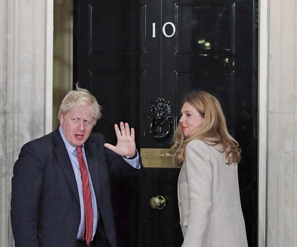 boris johnson and his girlfriend wave to the press as the enter 10 downing street.