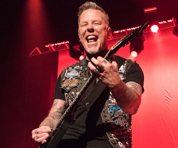 metallica's james hetfield jams out with mouth open showing teeth, strumming the guitar
