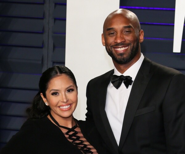 kobe bryant in a suit and black bow tie and vanessa bryant in a black lace up front dress