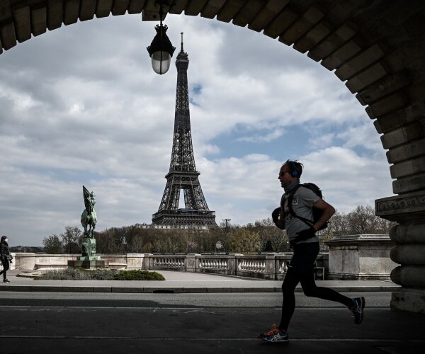 man wearing headphones jobs with eiffel tower in the background