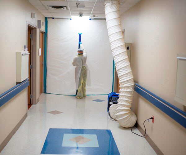 a healthcare worker closing a barrier near a coronavirus unit in a texas hospital