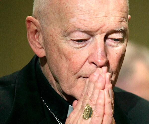 Former Cardinal Theodore McCarrick bows his face in his hands in prayer