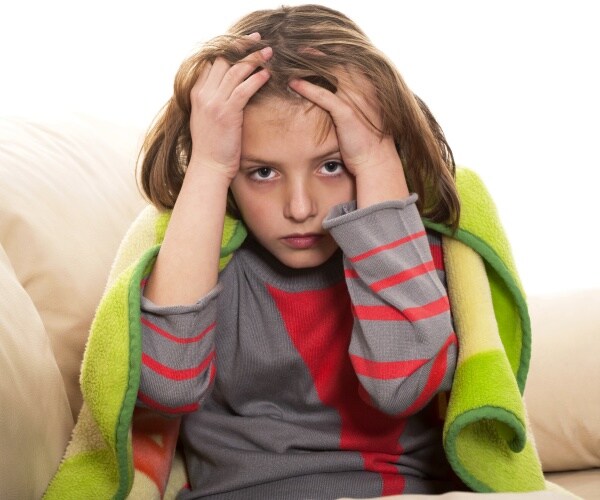 child feeling sick, holding head with headache