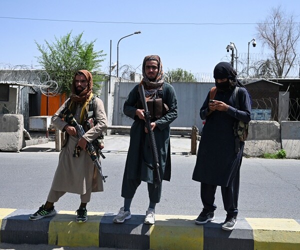 taliban soldiers stand in street with guns