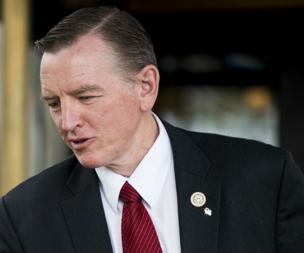 Paul Gosar is shown in a dark suit, dress shirt and red tie.