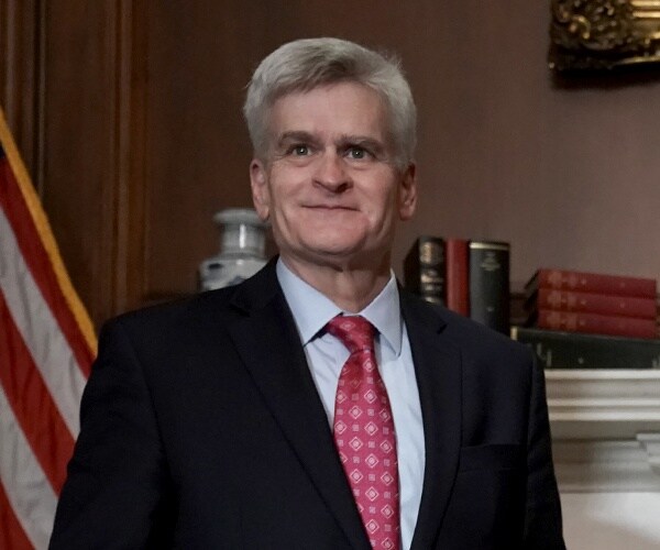 bill cassidy stands in front of flag