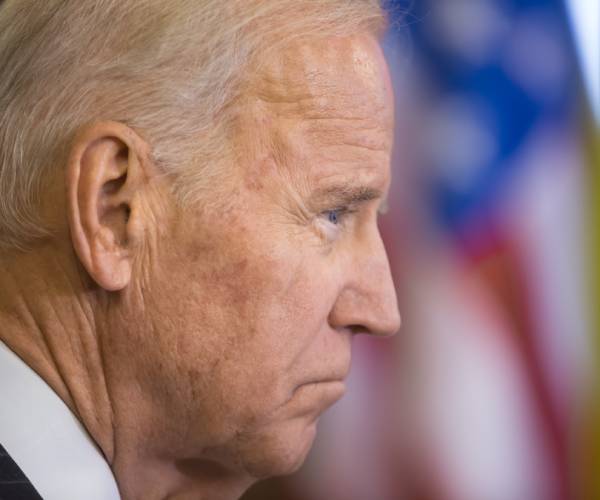 president biden looking sad with the american flag in the background