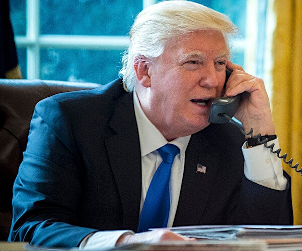 president donald trump speaks on the oval office telephone, holding it up to his left ear