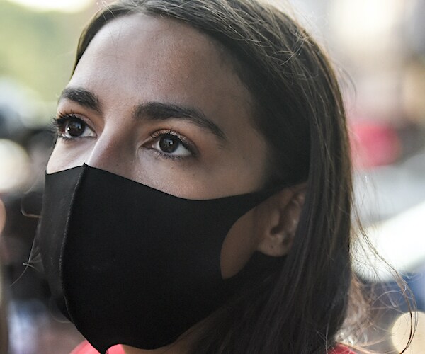 alexandria ocasio-cortez wears a black mask and looks up during a public appearance
