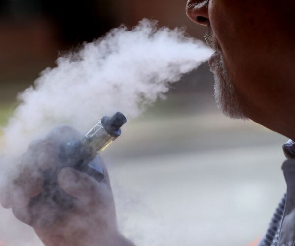 a man exhales while smoking an e-cigarette
