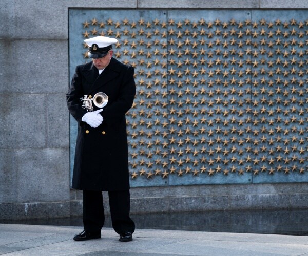 trumpeter stands by the ww2 memorial wearing a black coat
