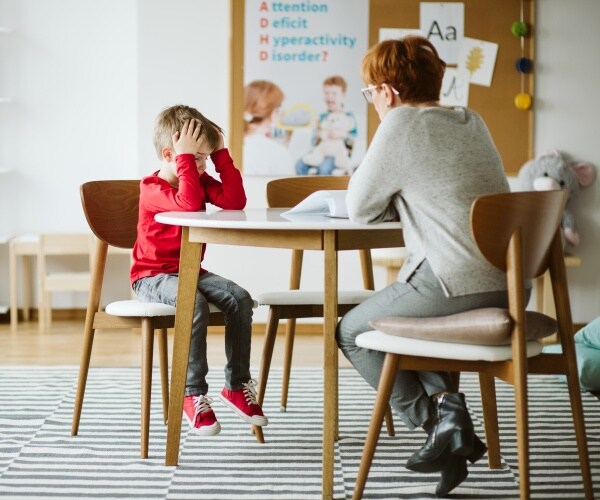 young boy with head in hands working in classroom with teacher