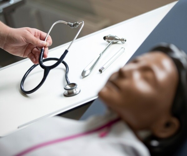 a stethoscope lies next to a resuscitation manikin 
