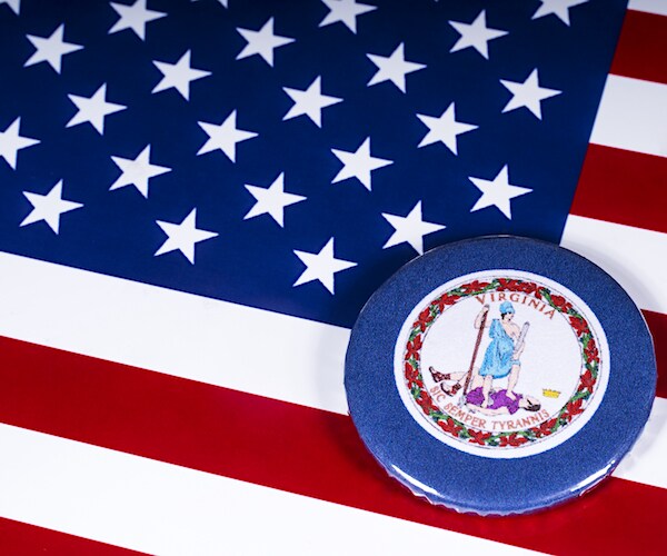 The symbol of the State of Virginia, pictured over the flag of the United States of America