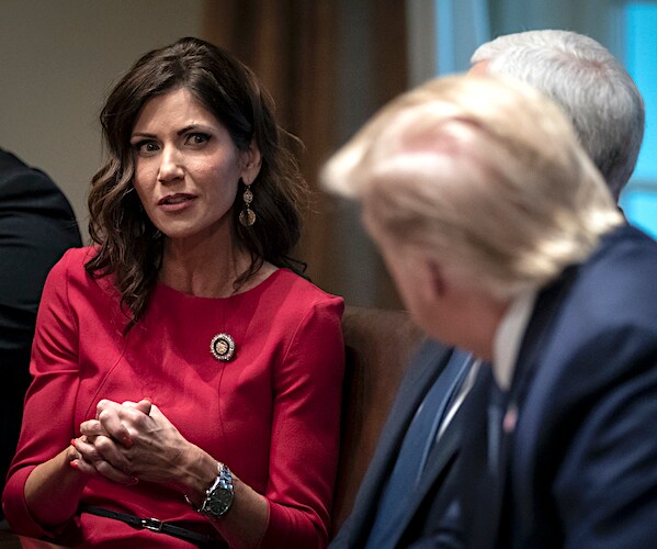 kristi noem clasps her hands while speaking to president donald trump in the cabinet room