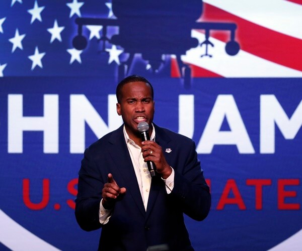 candidate john james stands at a mic at an election rally