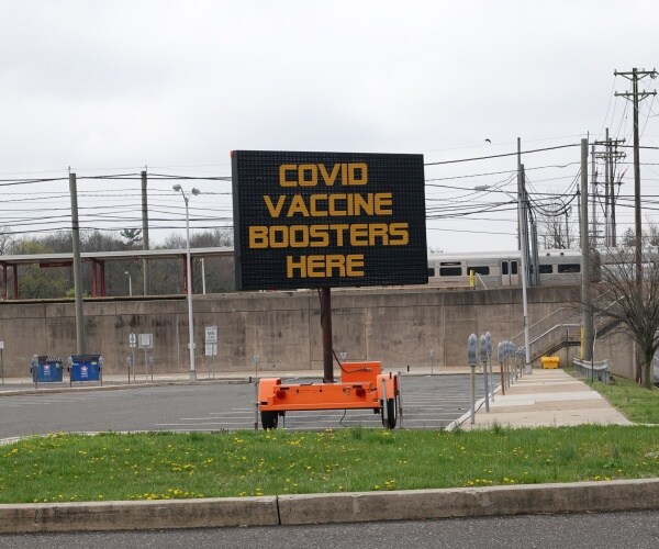 electronic road sign reads "COVID Boosters Here"