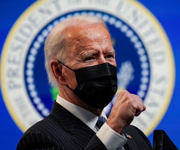 joe biden raises fist while wearing mask