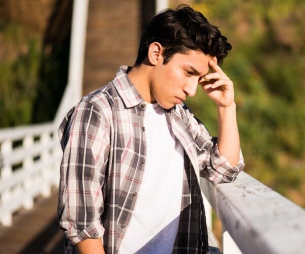 teen boy on bridge looking depressed, anxious