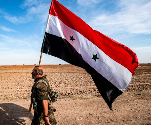 syrian flag in the desert carried by a syrian government soldier