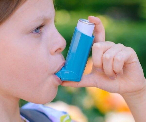 young girl using an inhaler for asthma