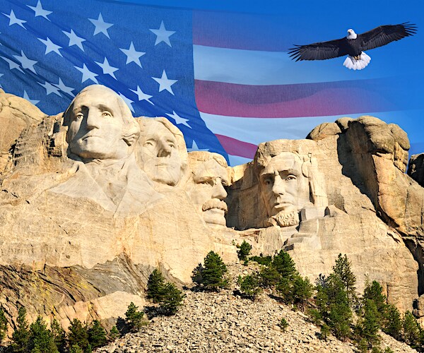 mount rushmore showing the presidents, a bald eagle flying by, and an american flag