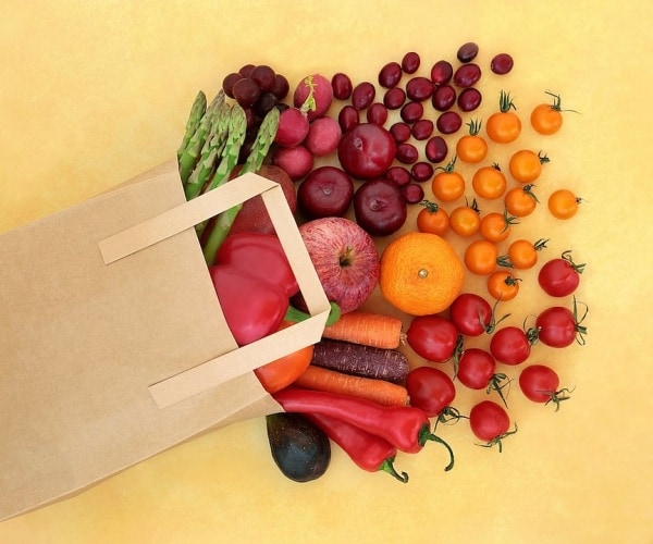 fresh produce, including tomatoes and other vegetables, spilling out of grocery bag