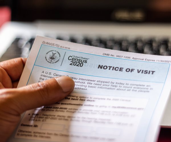 A hand holding a Notice of Visit from the US Census Bureau.