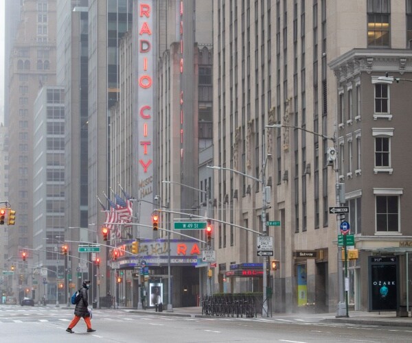 radio city hall is shown with a woman wearing a long winter coat and mask