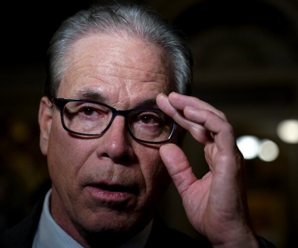 braun with black glasses puts his hand up to his head