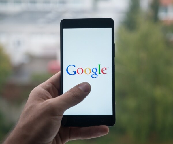 hand holding a smart phone displaying google logo