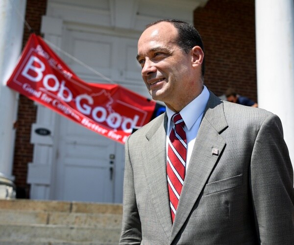bob good in a gray suit and red striped tie standing outside a courthouse