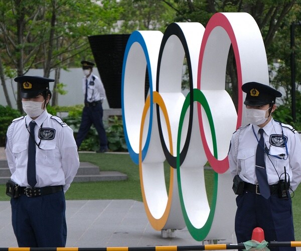 security guards stand in front of olympic rings