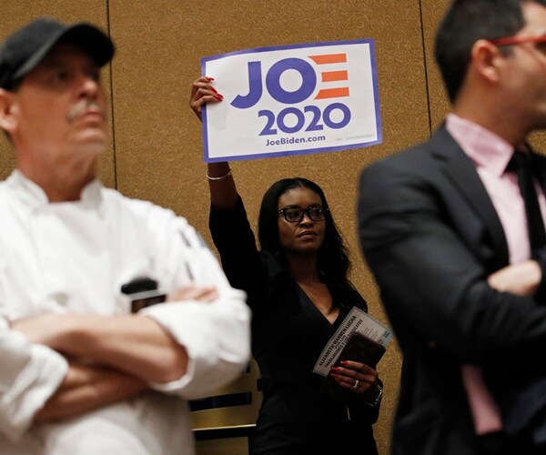 a woman holds up a sign in support of joe biden at the nevada caucuses in las vegas