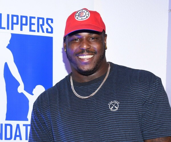 jackson in a gray and blue striped shirt and red la clippers baseball cap