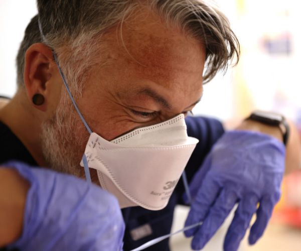 Nurse removes mask after emerging from a room in the acute care COVID-19 unit