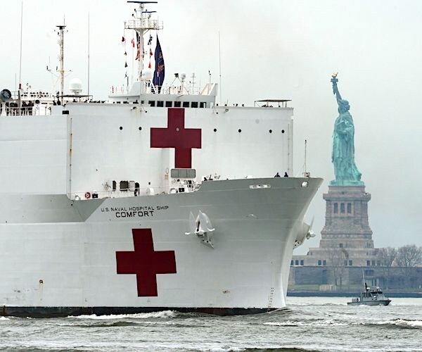 a naval hospital ship rolls into lower manhattan past the statue of liberty at the start of the pandemic