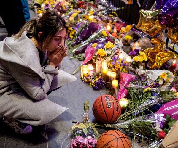 a fan pays her respects to the late kobe bryant at a makeshift memorial outside the staples center in los angeles