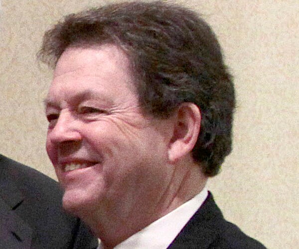 art laffer looks to his left and smiles wifde