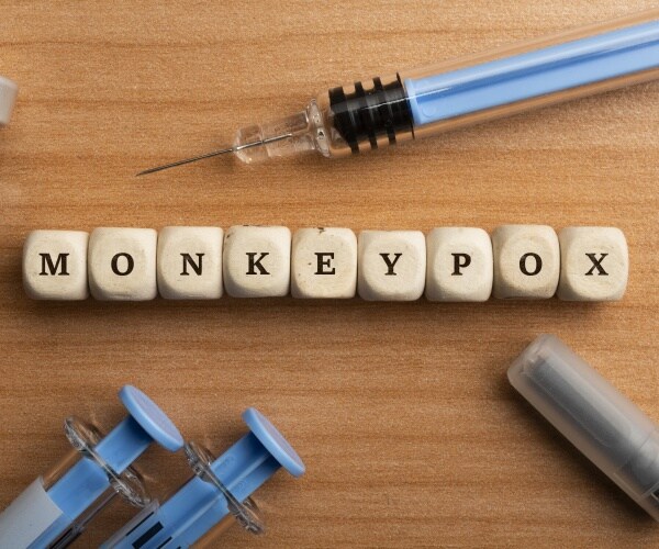 monkeypox spelled out in wood blocks, syringes around it