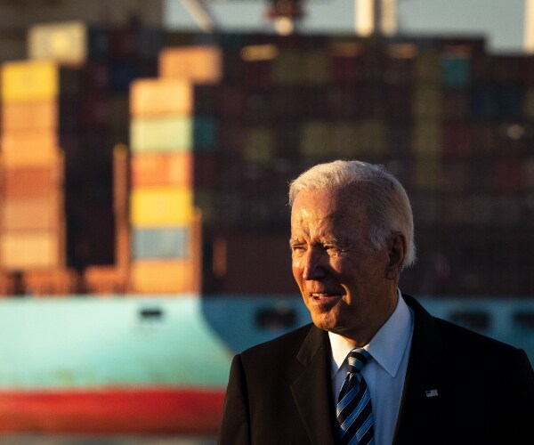 biden standing in front of shipping containers