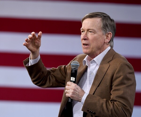 john hickenlooper campaigns in front of a flag