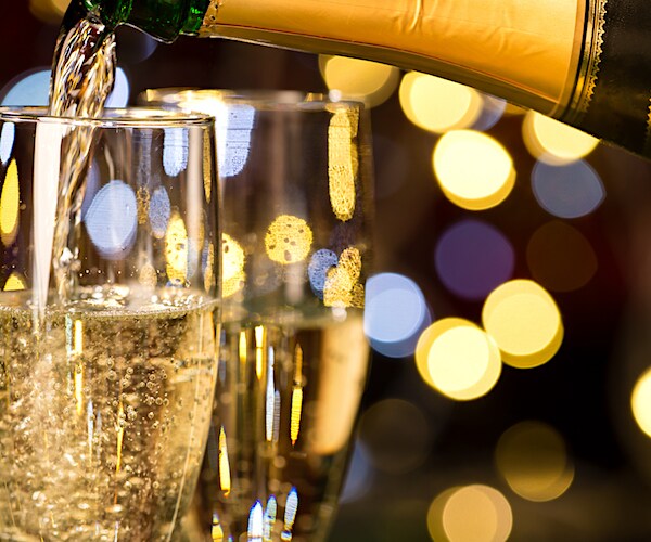 a pair of champagne glasses are filled with golden bubbly from a champagne bottle