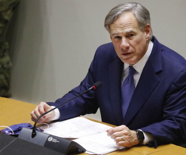 texas gov. greg abbott is shown speaking about covid-19 cases with his mask sitting beside papers