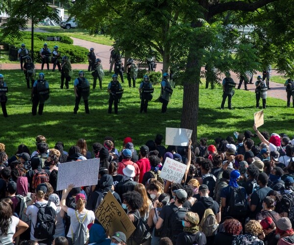 crowd of protesters close together in front of a row of police officers