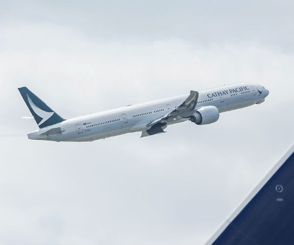 a blue and white passenger aircraft of the airline cathay pacific is climbing 