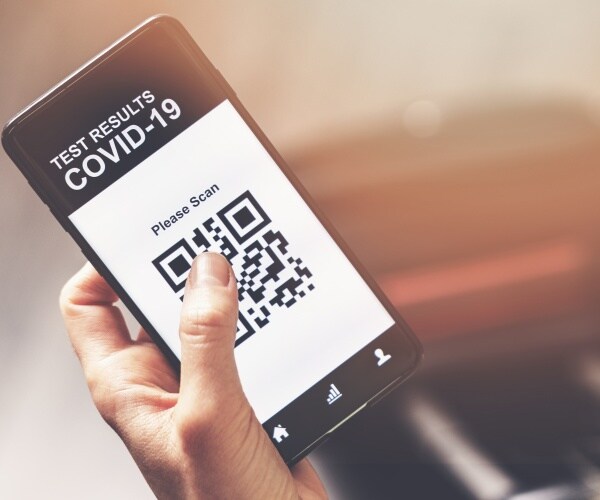 person holding a smartphone with COVID test results on it