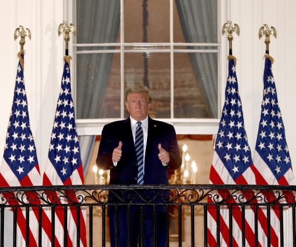 donald trump stands on balcony