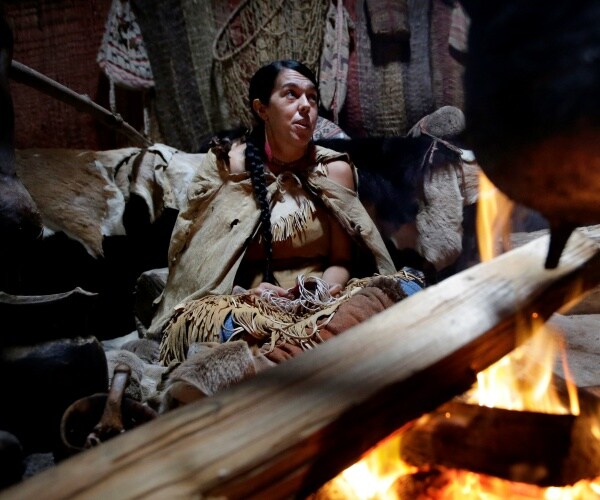 a native american weaves a basket