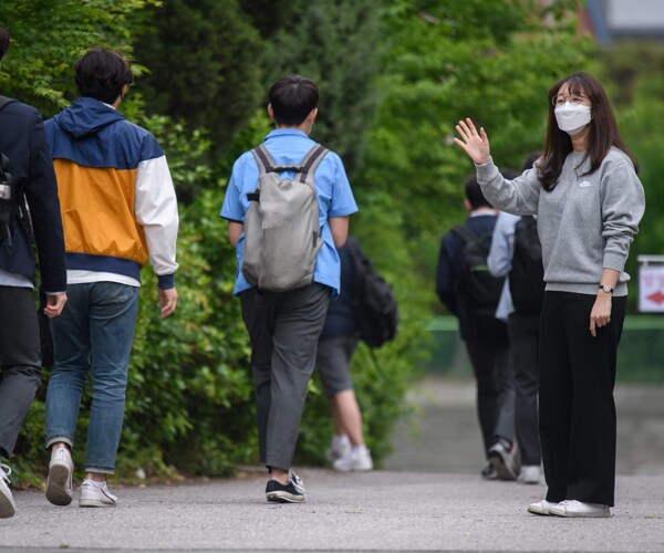 a teacher greets students at a school in south korea